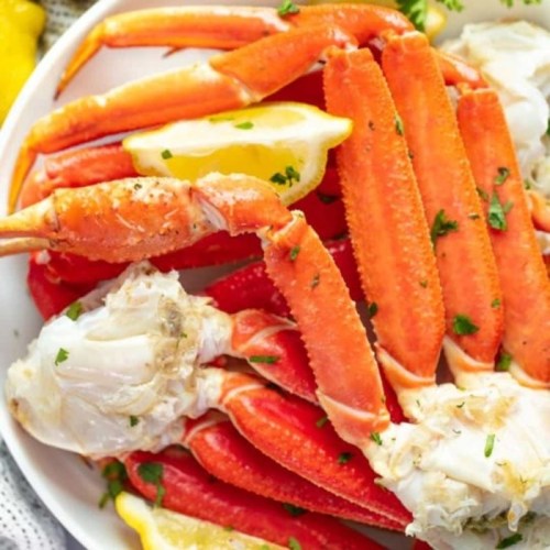 A plate of cooked crab legs garnished with lemon wedges and parsley.