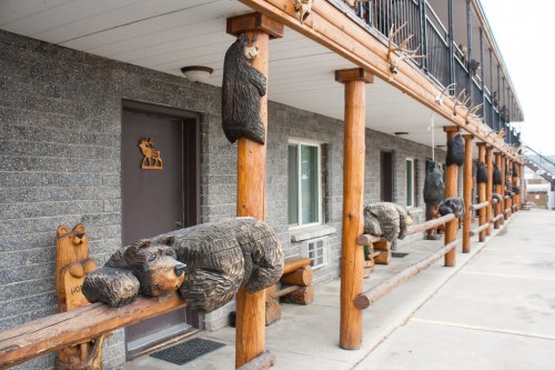 Wooden bear carvings decorate the porch of a rustic motel, adding a whimsical touch to the exterior.