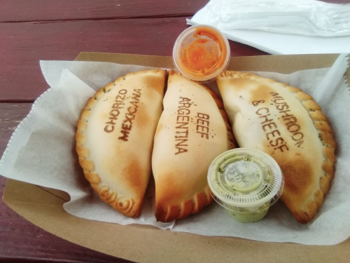 Three empanadas labeled "Chorizo Mexicana," "Beef Argentina," and "Mushroom & Cheese," with dipping sauces.