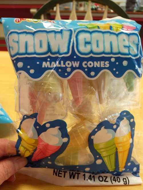 A hand holding a colorful package of snow cone mallow cones, featuring various cone designs and flavors.