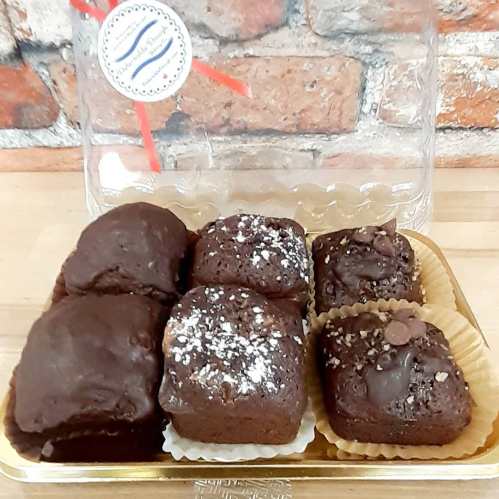 A box of assorted chocolate treats, including brownies and chocolate-covered squares, on a wooden surface.