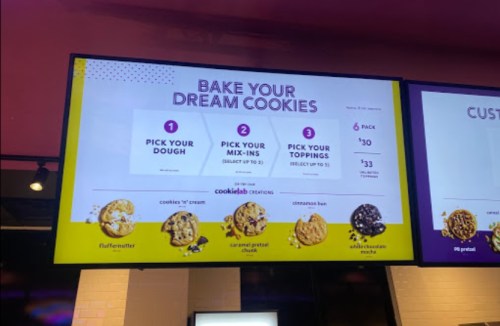 Menu board displaying options for customizing cookies: choose dough, mix-ins, and toppings with pricing details.