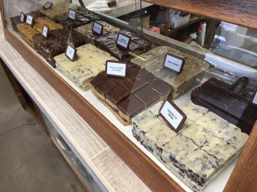 A display case filled with various types of fudge, labeled with flavors like chocolate, peanut butter, and cookies and cream.