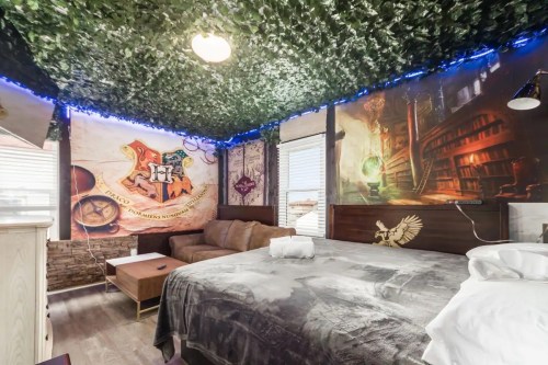 A themed bedroom with a leafy ceiling, cozy couch, and walls decorated with magical imagery and symbols.