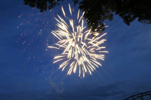 Colorful fireworks burst in the night sky, illuminating the dark blue backdrop with sparkling light.