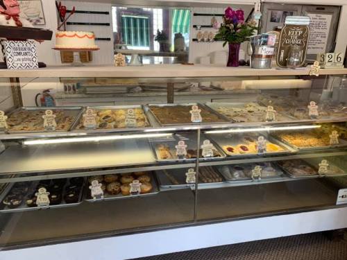 A display case filled with various baked goods, including cakes, cookies, and pastries, with price tags visible.
