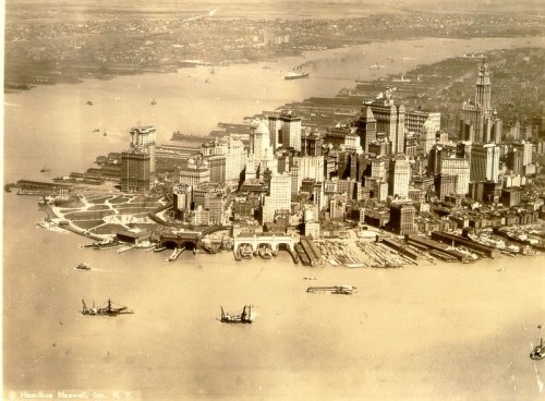 Aerial view of a historic city skyline with waterfront, ships, and bustling docks, in sepia tones.