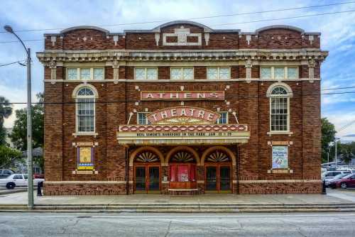 Historic Athens Theatre with a brick facade, marquee, and decorative arches, set against a clear sky.