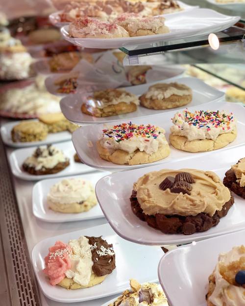 A display of various decorated cookies on white plates, featuring colorful sprinkles and frosting.
