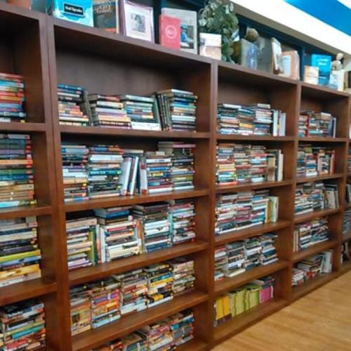 A wooden bookshelf filled with a large collection of various books in different colors and sizes.