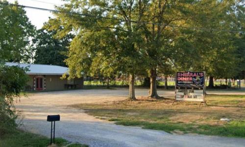 A diner building with a sign reading "Sherral's Diner," surrounded by trees and a gravel driveway.