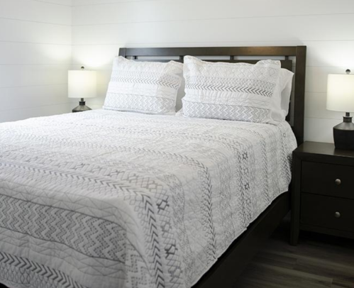 A cozy bedroom featuring a double bed with a patterned quilt and two bedside lamps on dark wood nightstands.