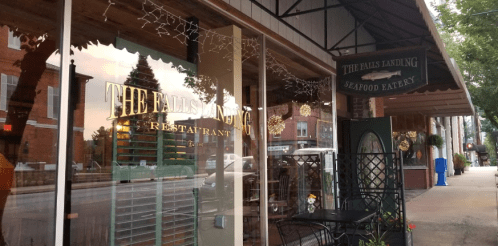 Exterior view of The Falls Landing restaurant, featuring large windows and festive decorations along the street.