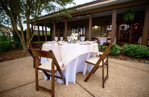A beautifully set outdoor dining table with a floral centerpiece, surrounded by wooden chairs.