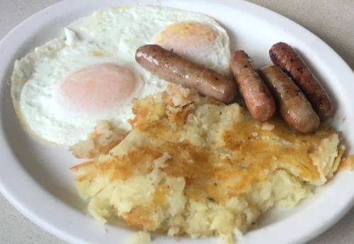 A plate with two fried eggs, three sausage links, and a serving of hash browns.