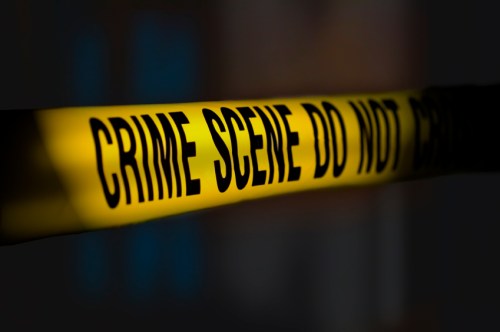 Yellow crime scene tape with the text "CRIME SCENE DO NOT CROSS" against a dark background.