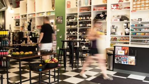 A vibrant store interior with shelves of products, a checkered floor, and customers browsing.