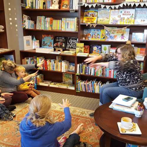 A children's storytime session in a cozy bookstore, with a woman reading to kids and parents seated around her.