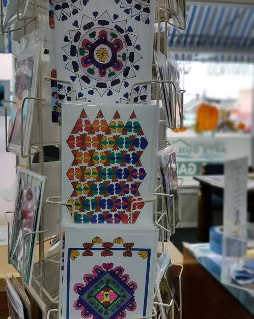 A display rack featuring colorful, patterned greeting cards with floral and geometric designs.