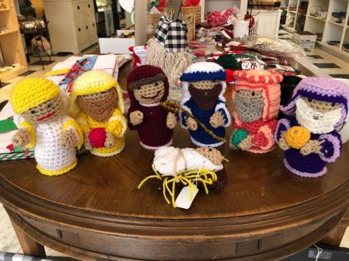 A collection of crocheted figures representing a nativity scene, including Mary, Joseph, and various wise men.