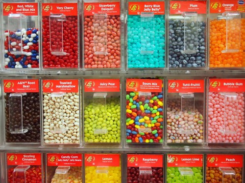 A colorful display of jelly beans in various flavors, organized in clear containers with labels.