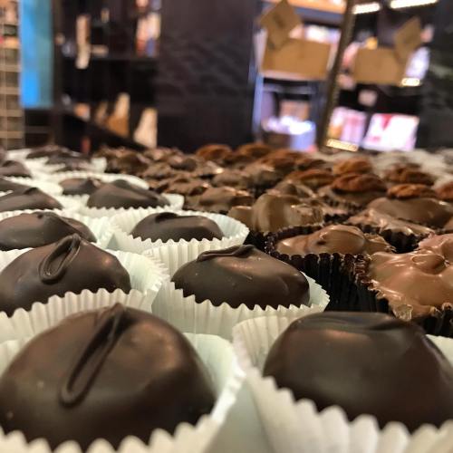 A close-up of assorted chocolate truffles arranged in white and dark wrappers on a display.