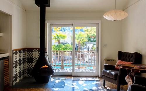 Cozy interior with a modern fireplace, a chair, and large sliding doors opening to a sunny outdoor area with palm trees.