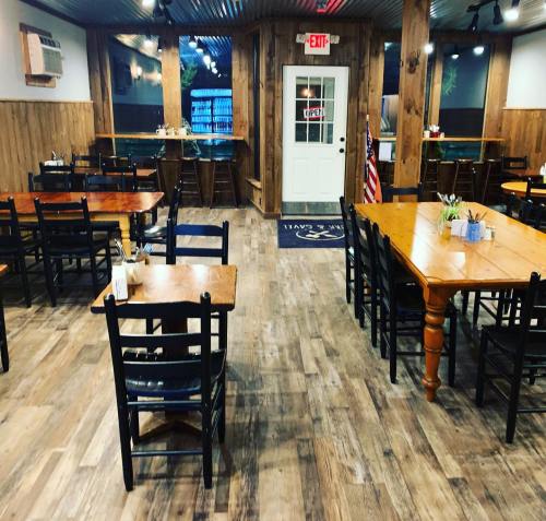 Interior of a rustic restaurant with wooden tables and chairs, featuring a welcoming atmosphere and an open sign.