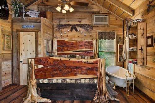 Cozy wooden cabin interior featuring a rustic bed, clawfoot tub, and natural decor elements. Warm and inviting atmosphere.