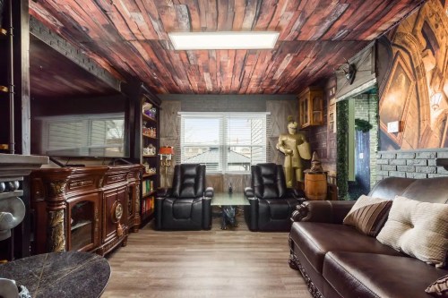 Cozy living room with wooden ceiling, leather sofa, recliners, and decorative elements, including a statue and bookshelves.