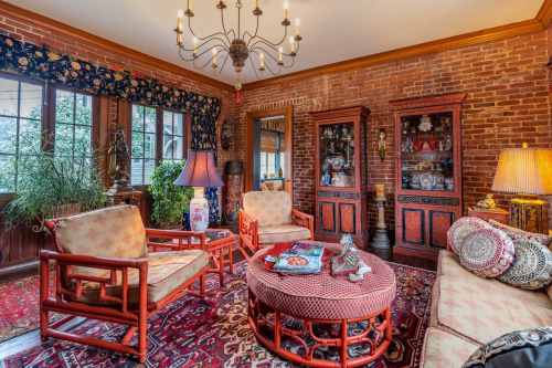 Cozy living room with brick walls, vintage furniture, colorful rugs, and decorative lamps.