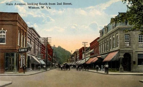 Historic postcard of Main Avenue in Weston, W.Va., showing storefronts and horse-drawn carriages on a sunny day.