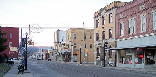 A quiet street scene featuring buildings, shops, and traffic lights in a small town during early evening.