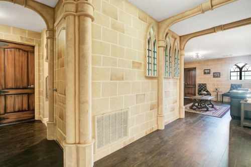 A cozy interior featuring stone walls, wooden doors, and a living area with arched windows and elegant furnishings.