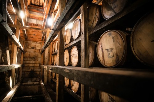 A dimly lit wooden cellar filled with stacked barrels on shelves, showcasing a rustic storage space.