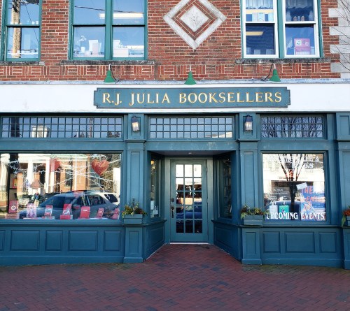 Entrance of R.J. Julia Booksellers, featuring large windows and a sign above the door, set in a brick building.