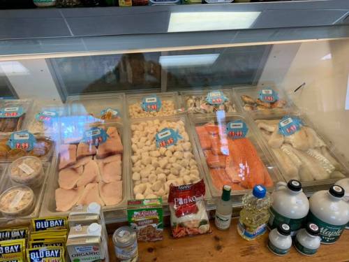 Display case filled with various seafood, including fish fillets, scallops, and shrimp, with price tags visible.