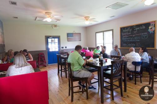 A cozy restaurant interior with diners at tables, a chalkboard menu, and an American flag on the wall.