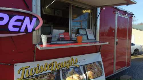 A red food truck with an "OPEN" sign, featuring a menu and a sign for Twisted Doughs.