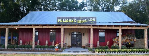 A rustic general store with a metal roof, wooden accents, and seasonal decorations in front.