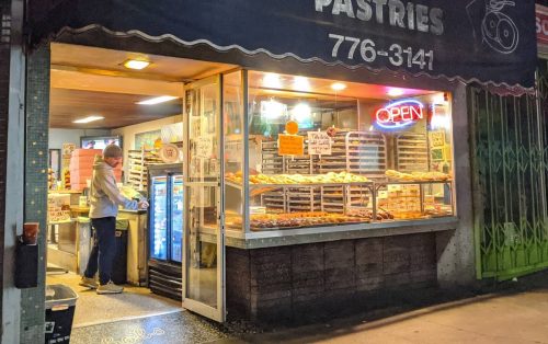 A storefront of Bob's Donuts and Pastries, featuring a bright "OPEN" sign and a display of donuts inside.