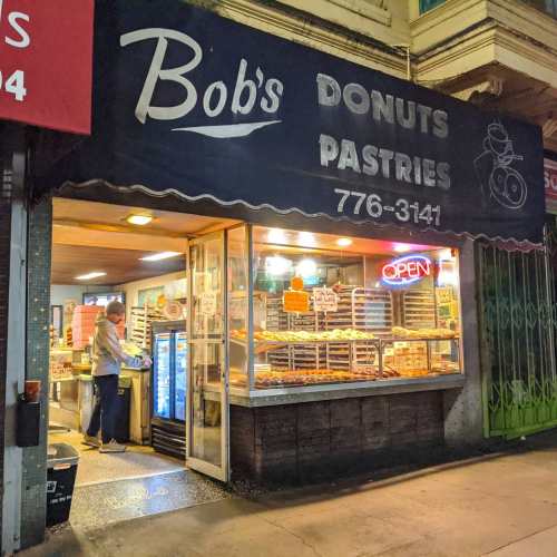A storefront of Bob's Donuts and Pastries, featuring a bright "OPEN" sign and a display of donuts inside.