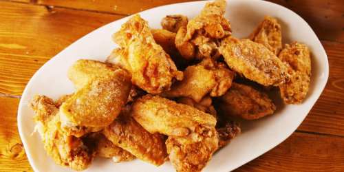 A platter of crispy, golden-brown fried chicken wings on a wooden table.