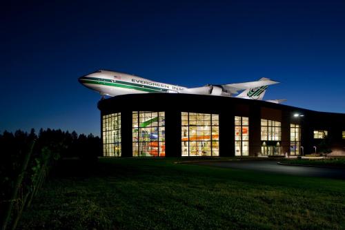 A large airplane mounted on a building at night, with illuminated windows showcasing colorful aircraft inside.