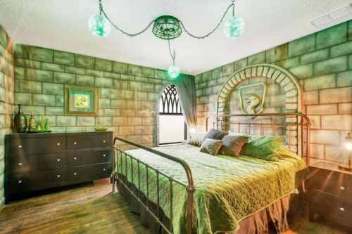 A cozy bedroom with green walls, a metal bed, and decorative lighting, featuring a castle-like design.