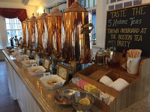 A display of copper tea urns and condiments for tasting historic teas, with a sign about the Boston Tea Party.