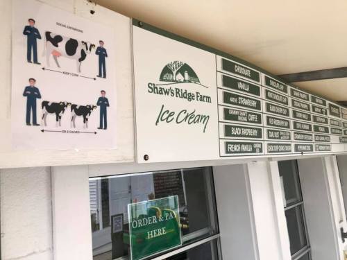 Signage at Shaw's Ridge Farm Ice Cream showing social distancing guidelines and a menu of flavors.