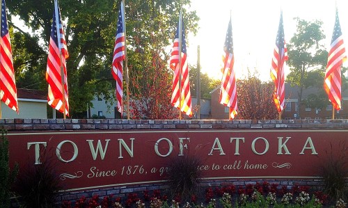 Sign for the Town of Atoka, featuring American flags and the text "Since 1876, a great place to call home."