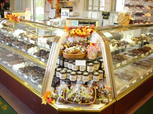 A display case filled with various chocolates, candies, and baked goods, decorated with autumn leaves.