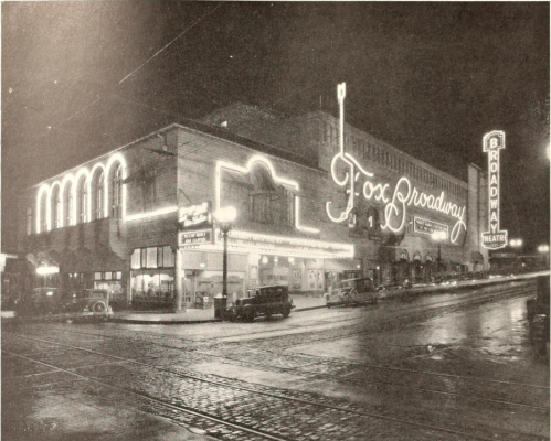 Historic night view of the Fox Broadway Theatre, illuminated with neon lights, surrounded by vintage cars and streetcars.